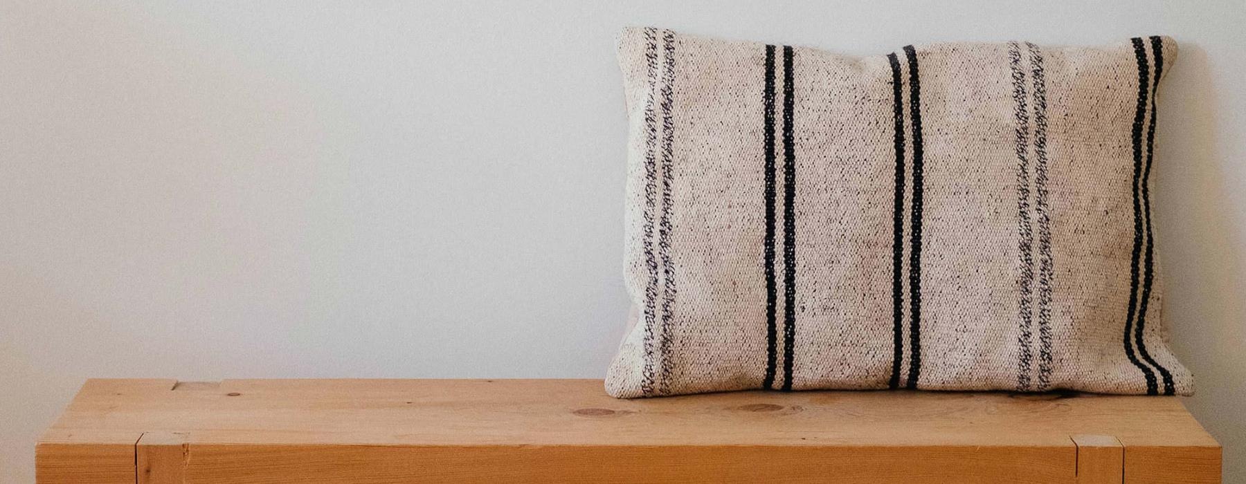 a wooden bench with a striped pillow on it