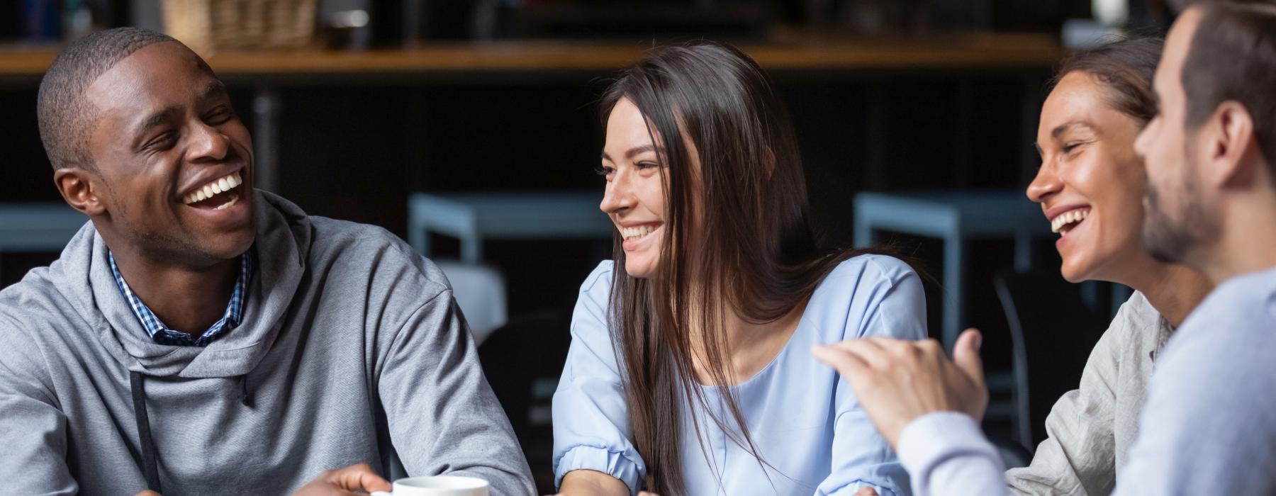 a group of people having a discussion with mugs in their hands