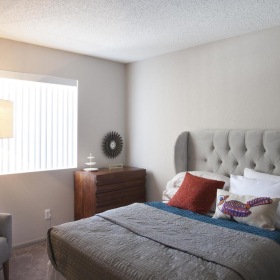 a bedroom with a bed chair window and lamp